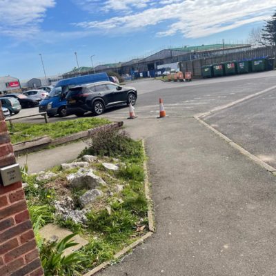 View of a small car park next to the path to the building entrance.