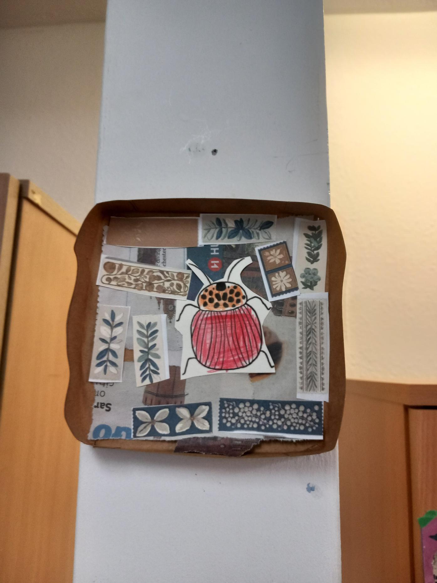 Media (15) Bug box with magazines and pictures of plants and flowers, with a red paper beetle on top.