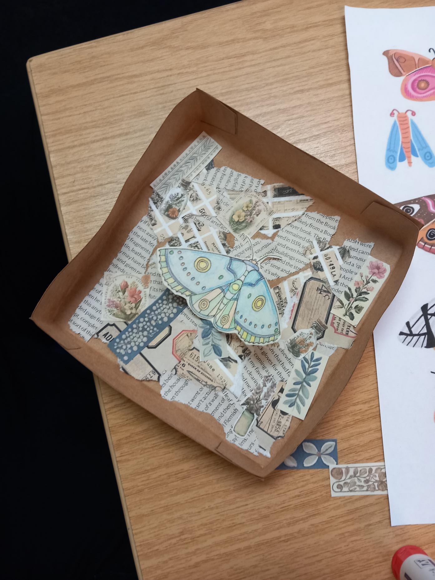 Media (16) Bug box containing a collage of text and flowers from magazines and a blue paper butterfly on top