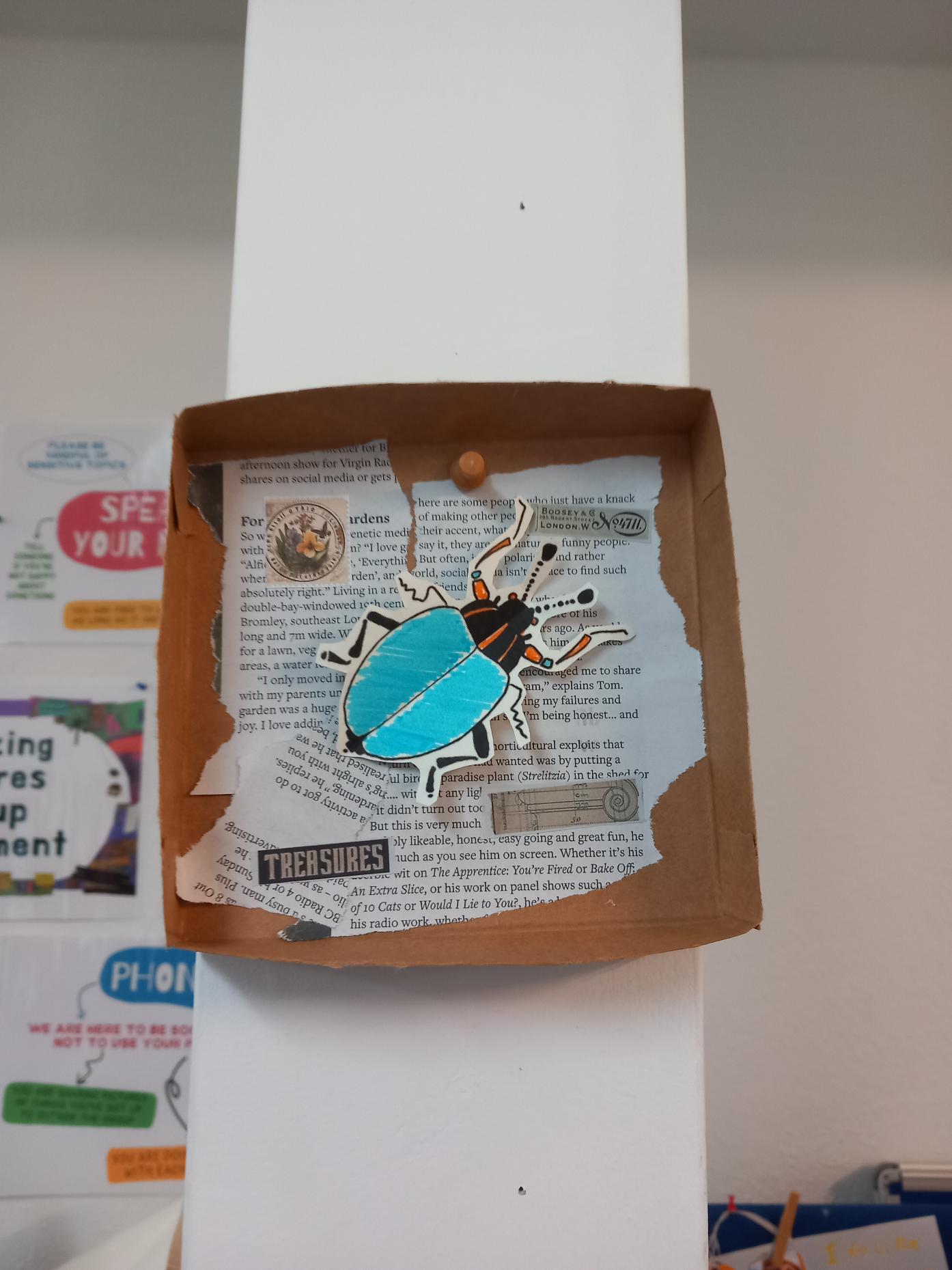 Media (17) Bug box with torn magazine text and a blue paper beetle