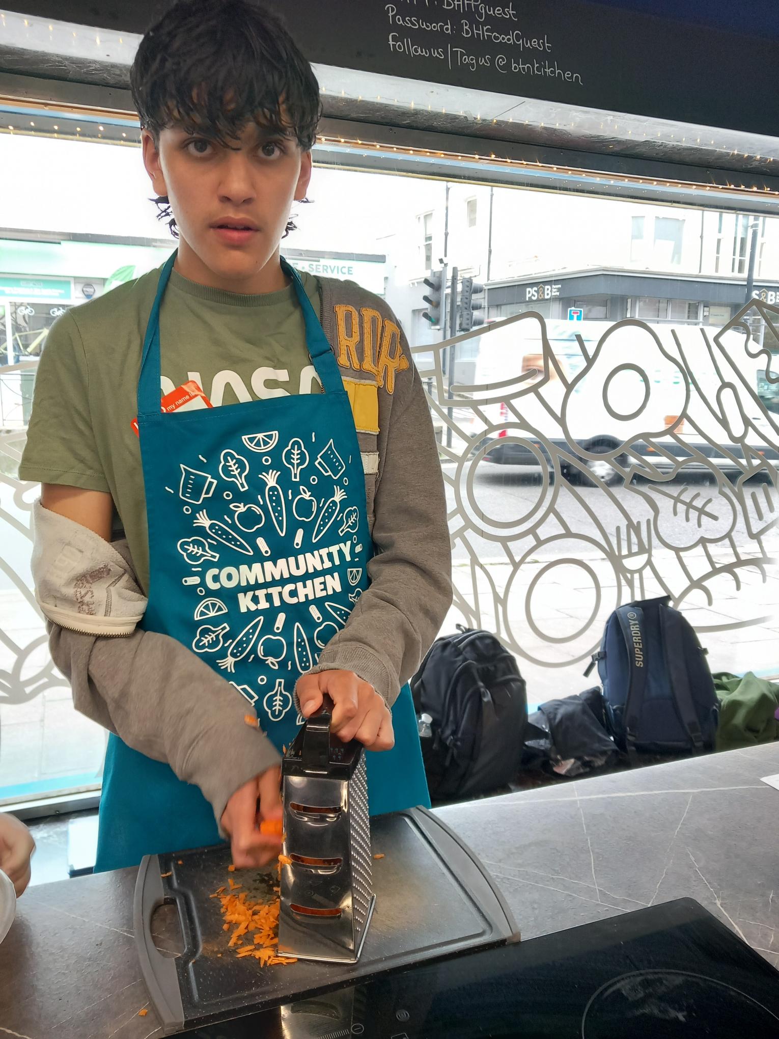 shared image (1) A young person in a Nasa t-shirt grating carrot at our baking session.