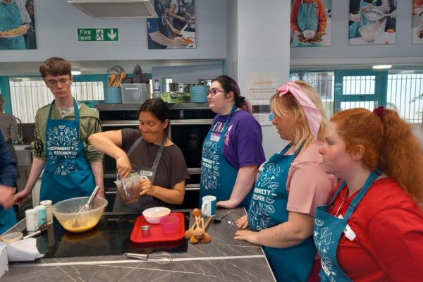 Young people at our baking session watching Anna from Brighton and Hove Food Partnership demonstrate how to make the cupcakes.