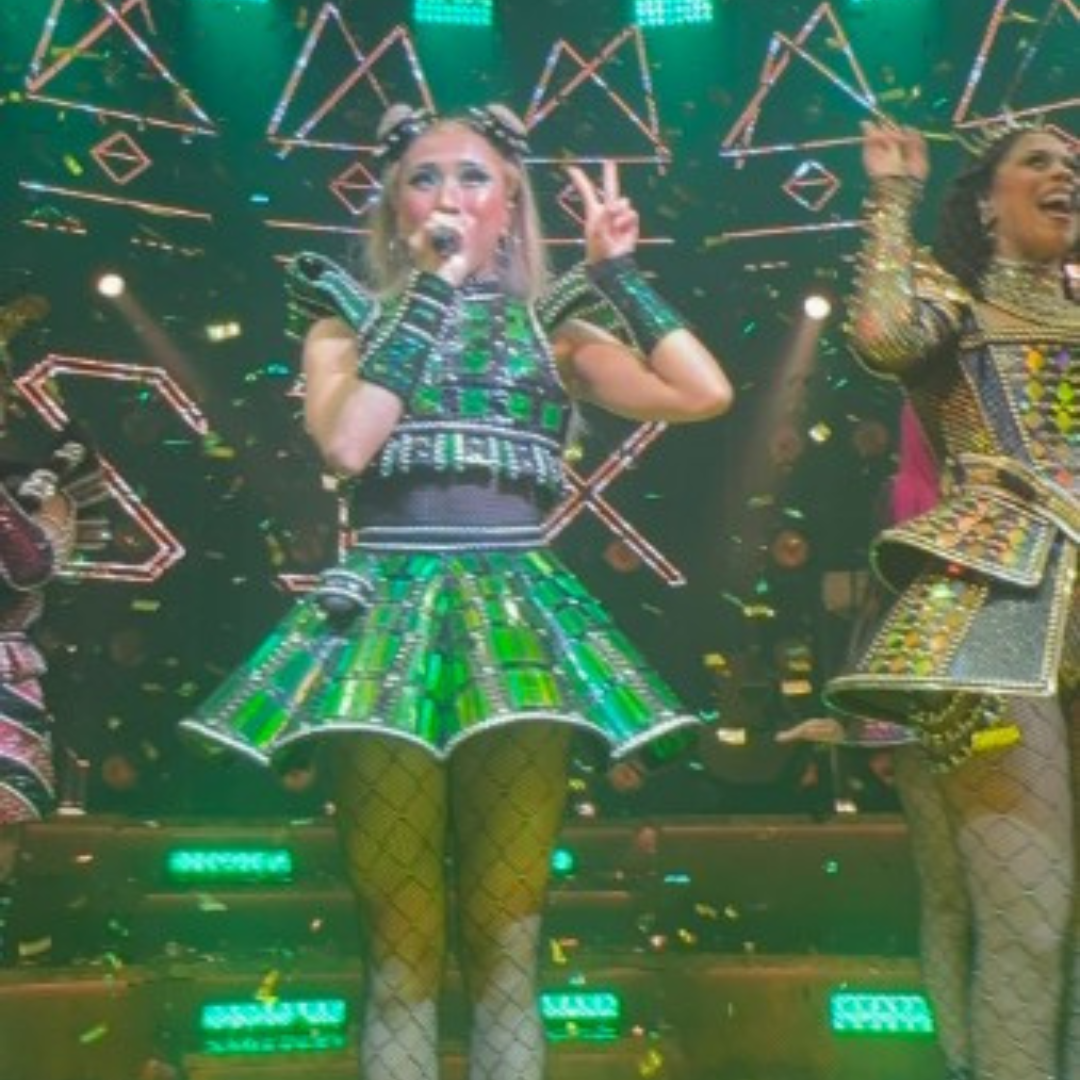 7 Actress in the green dress singing and making a peace sign.