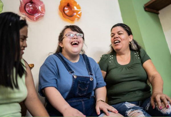 Three women sit indoors laughing together.
