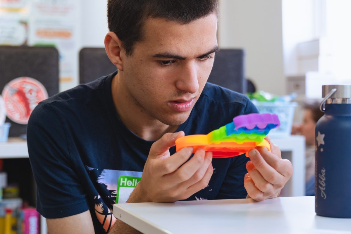 Young person looking at a rainbow fidget toy
