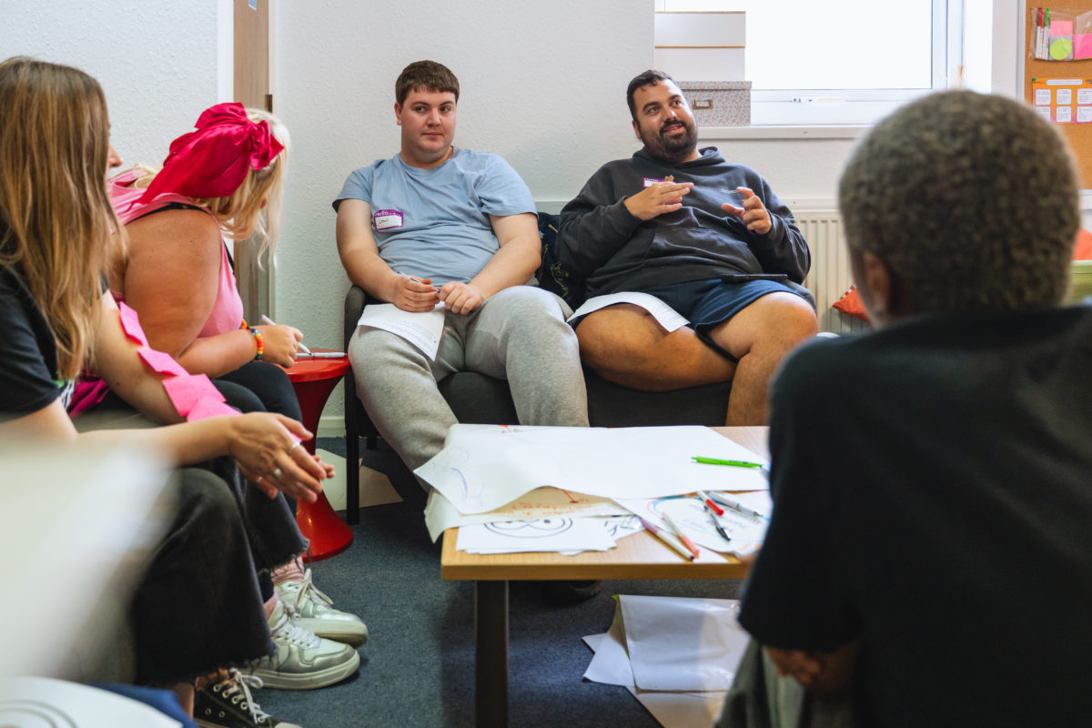 Young people sat around a table with papers and pens on.