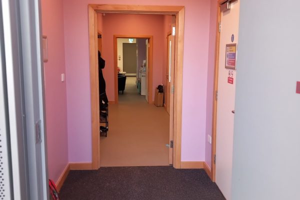 Inside the front door. A corridor with wide door openings. The walls are pink.