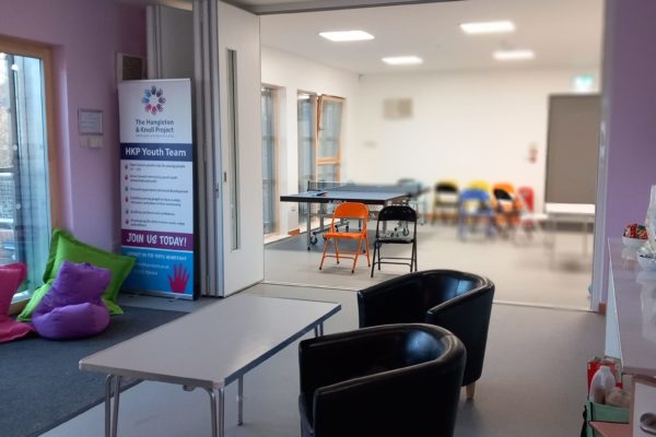 The main space. There are comfy padded chairs and folding chairs. It is a wide open space with lots of room. THere is a ping pong table, and brightly coloured beanbags.