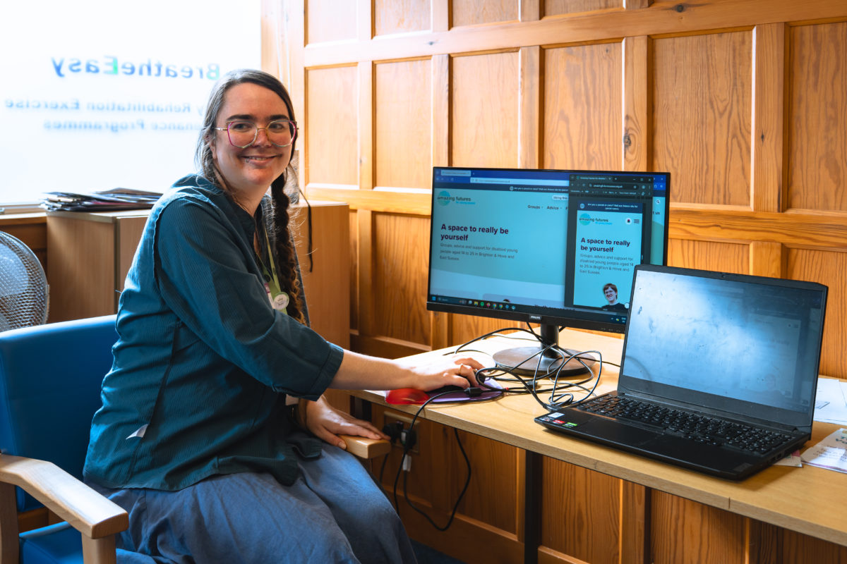 Rose from ther Comms team sat next to a computer displaying the Amazing Futures website.