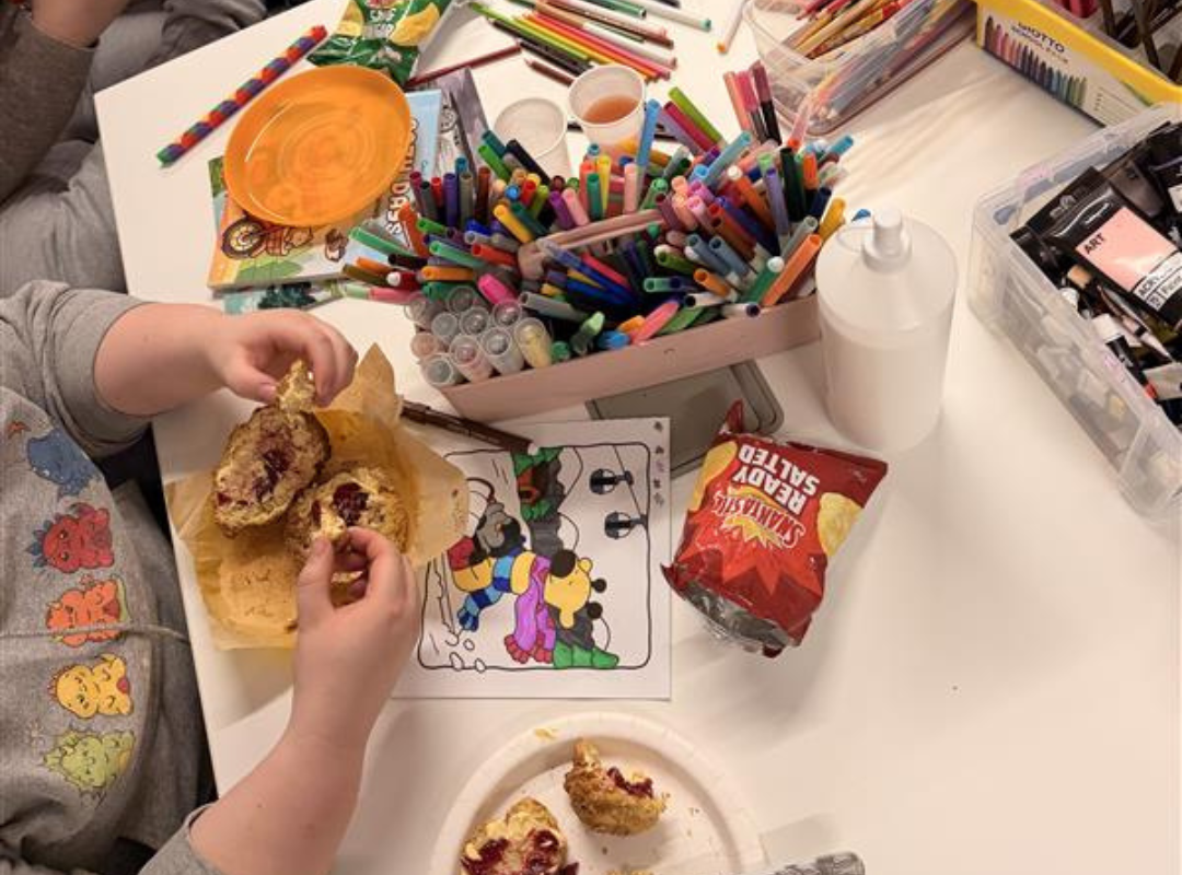Young person eating their roll, spread with jam and butter.