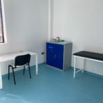 A plain, small room, with a table and chair and nothing on the walls.