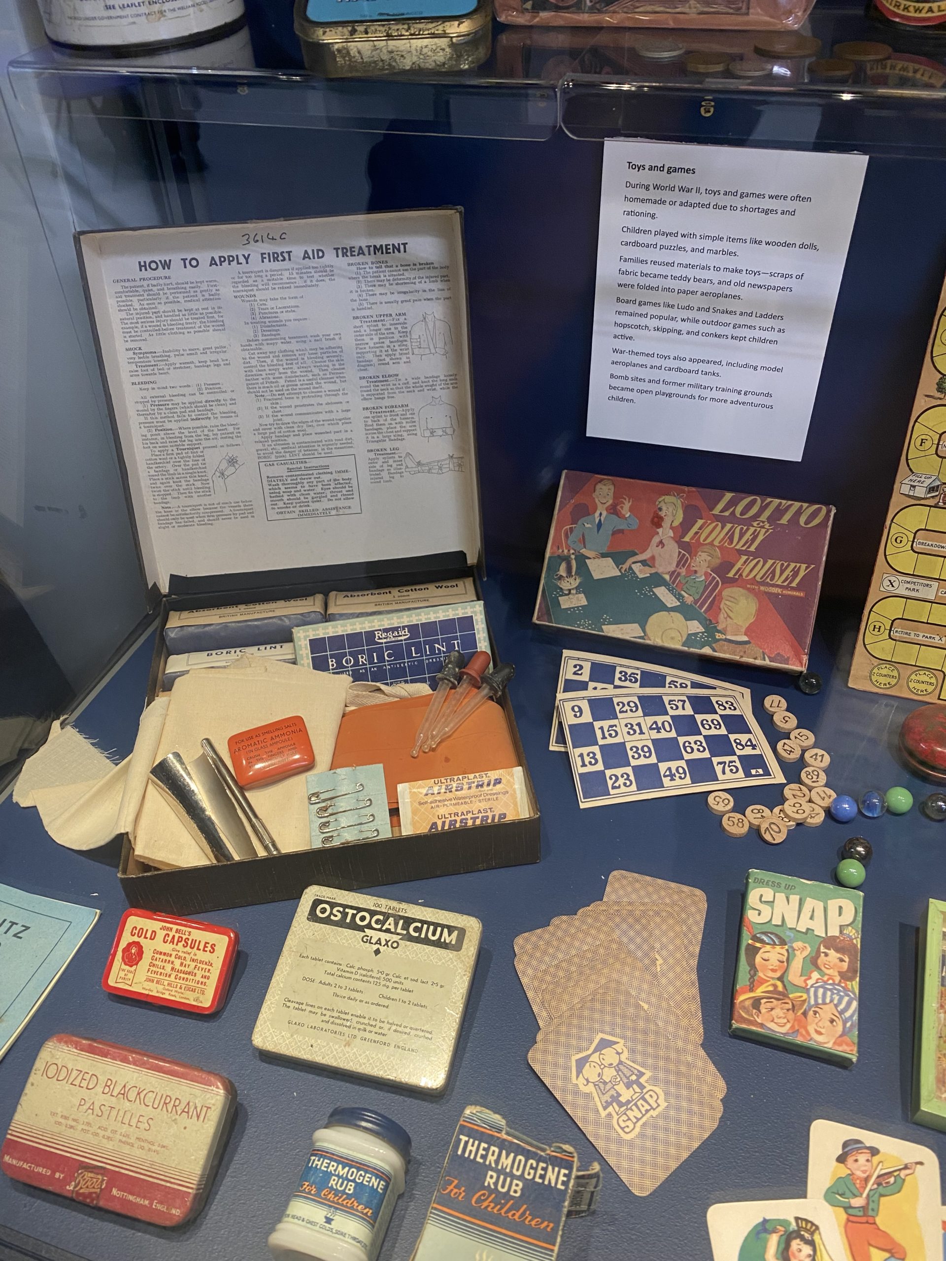 Display showing vintage children's toys and games, along with a vintage first aid kit and medical supplies.