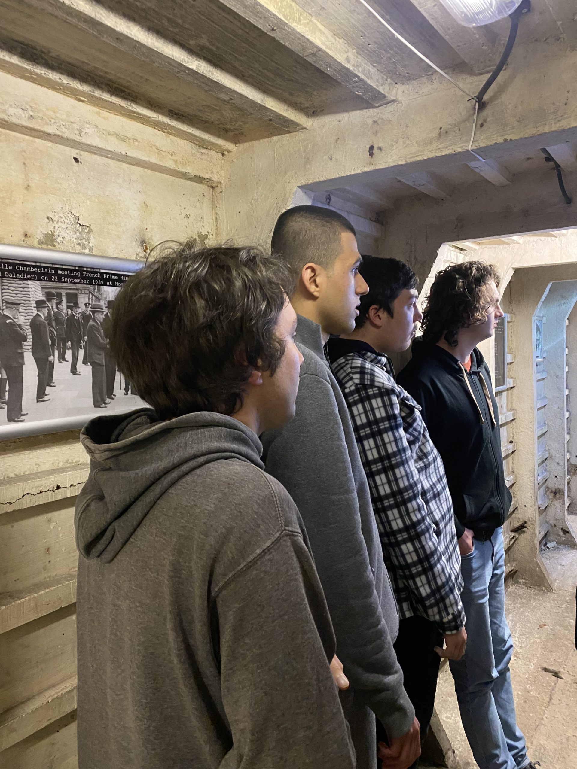 Row of young people in a tunnel looking at something off camera.