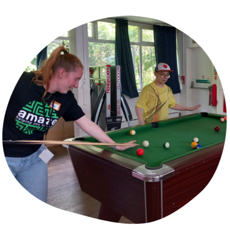 Youth worker in an Amaze t-shirt playing pool with a young person