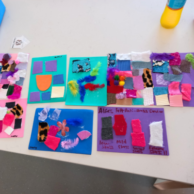 1 Colourful sheets of card with shapes of card and textiles stuck on, as well as feathers and flowers.