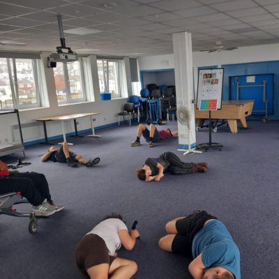 16 Lots of young people lying on the floor as if sleeping, as part of a game.