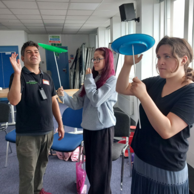 17 Man teaching two young people how to spin plates.