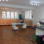 A seating area in the kitchen. There is a trestle table and padded seats, and space for several more tables.