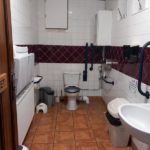 Open door leading to the disabled toilet. There is lots of space, and a tiled floor.