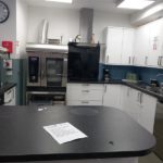 Kitchen with lots of workspace, cupboards, sink, a cooker, and various equipment. It looks in good condition.